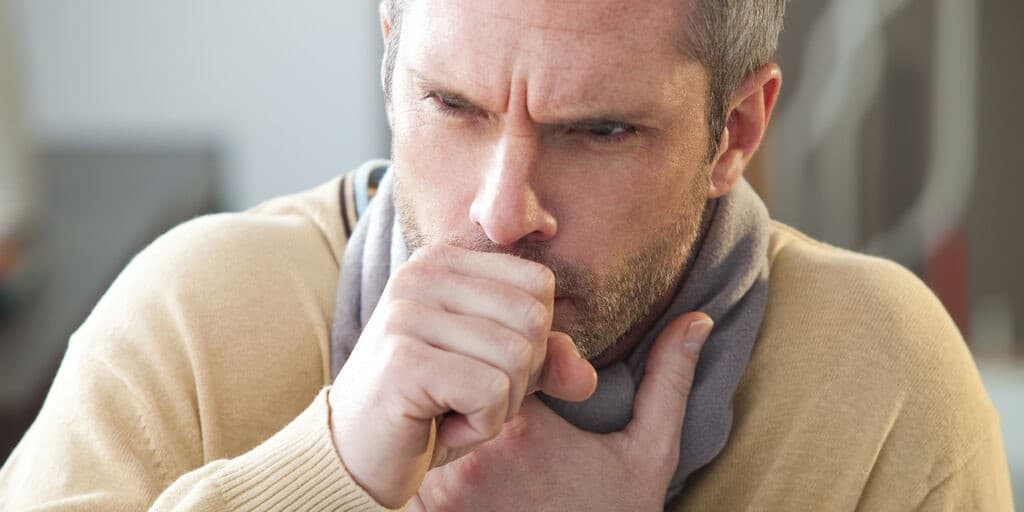 Angina wirusowa u mężczyzny, który kaszle i chwyta się za gardło
